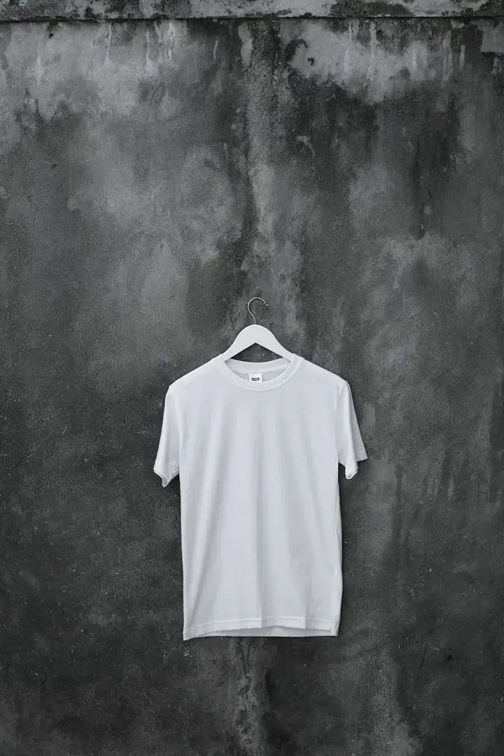 Plain white cotton top hanging against a dark wall